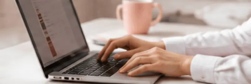 Dłonie piszące na laptopie przy biurku